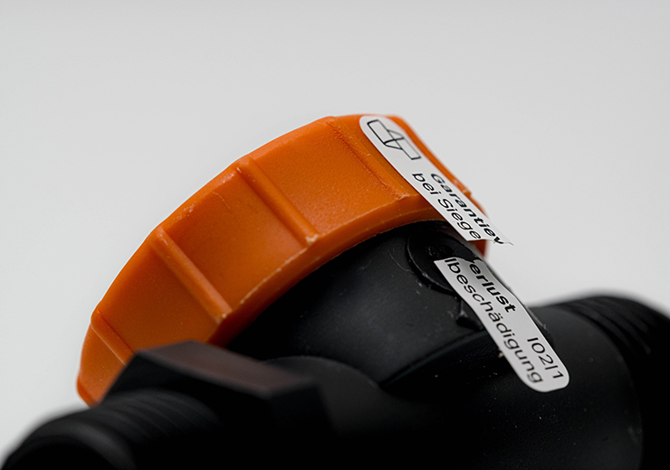 etikett-klebeplombe-auf-schwarz-orangen-kunststoff-bauteil-im-detail