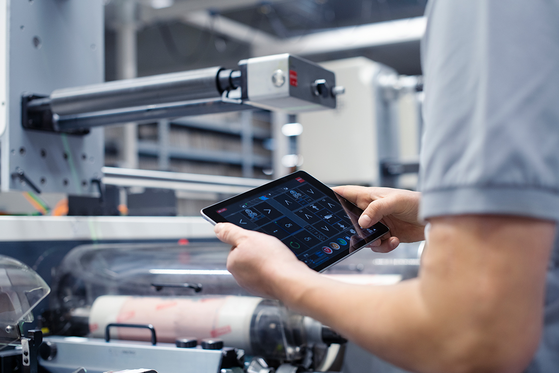 mitarbeiter-vor-flexodruckmaschine-mit-tablet