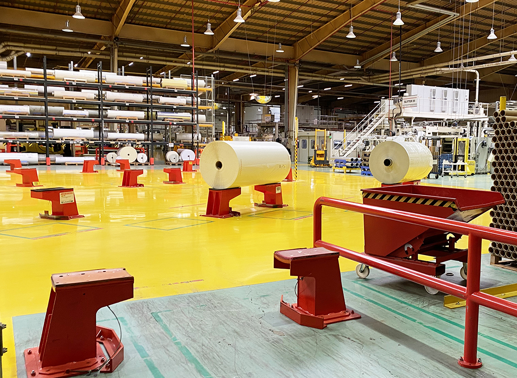 The huge rolls of material are temporarily parked on these supports.