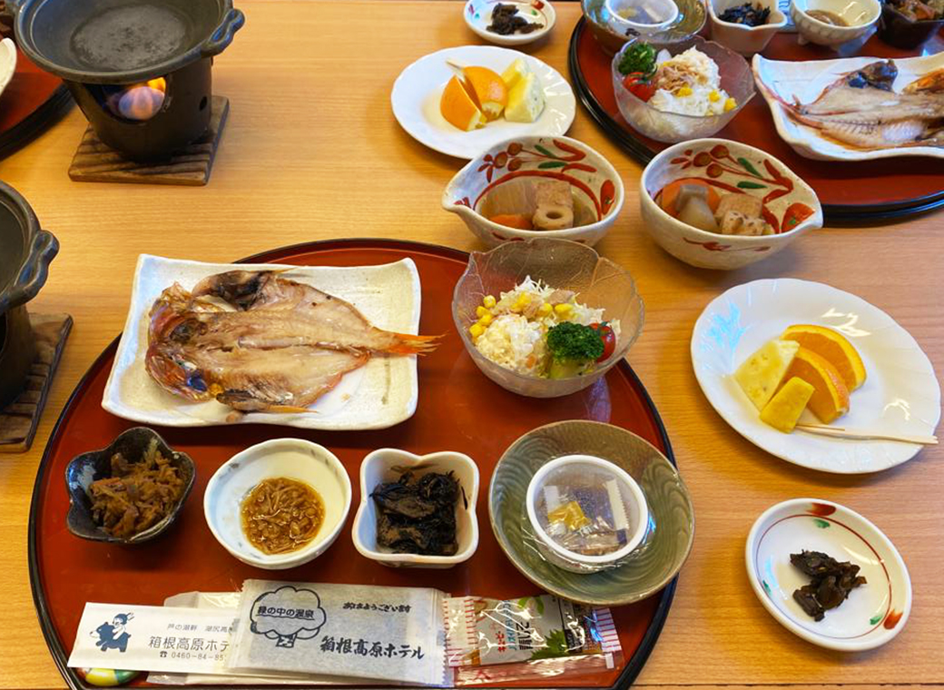 Traditional Japanese breakfast with soup, rice, pickled vegetables, seaweed, grilled fish, fruit and "nattō" - fermented soybeans.